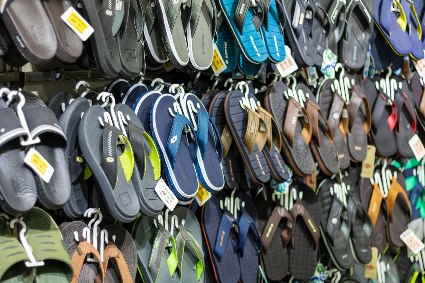 Colorful sandals and flip-flops hanging on a retail store wall.