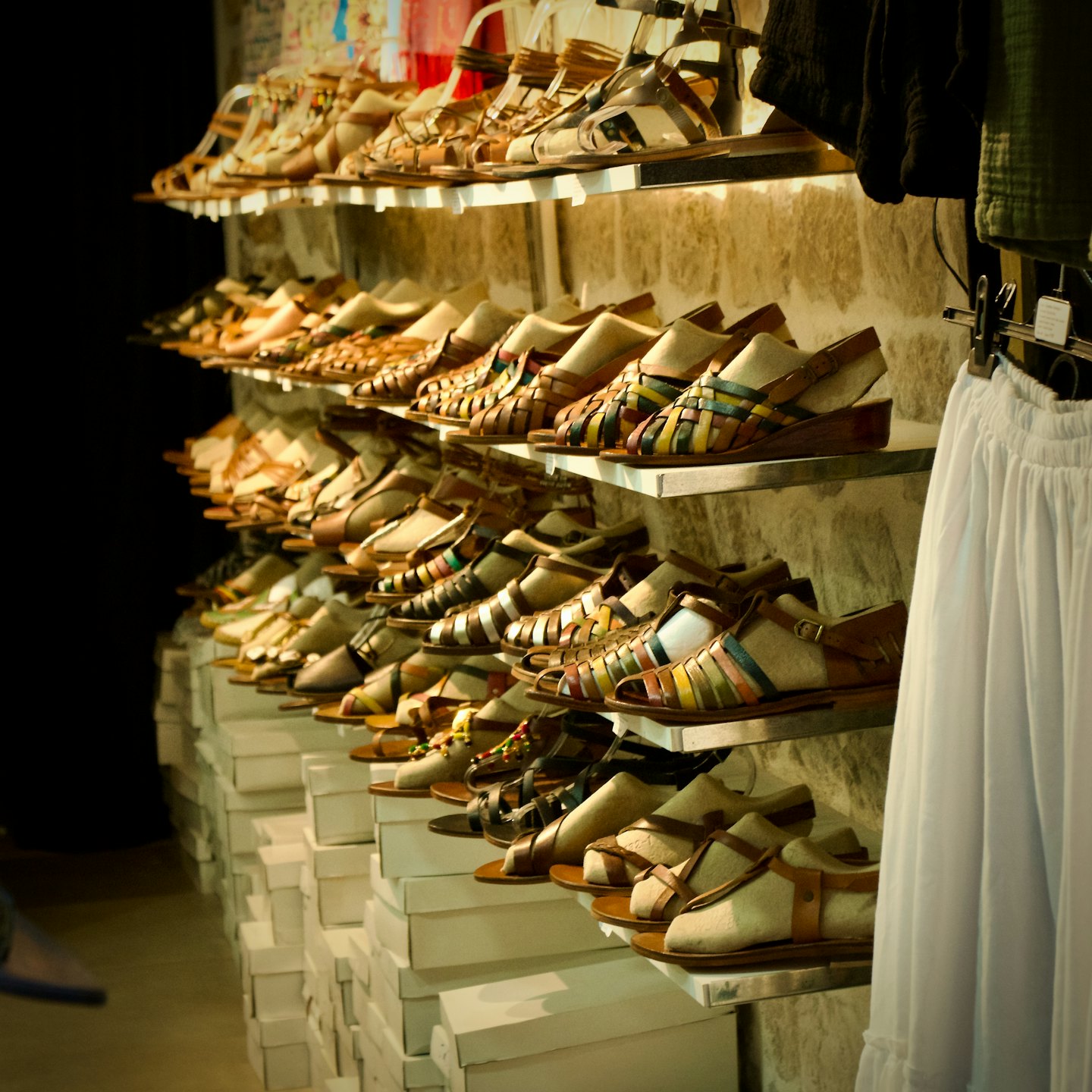Colorful woven leather sandals displayed on shelves in a shop.