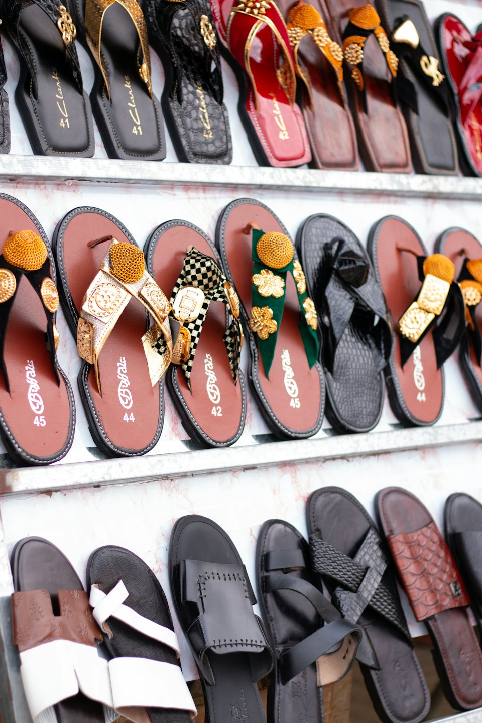 Assorted traditional and modern sandals displayed neatly on retail shelves.