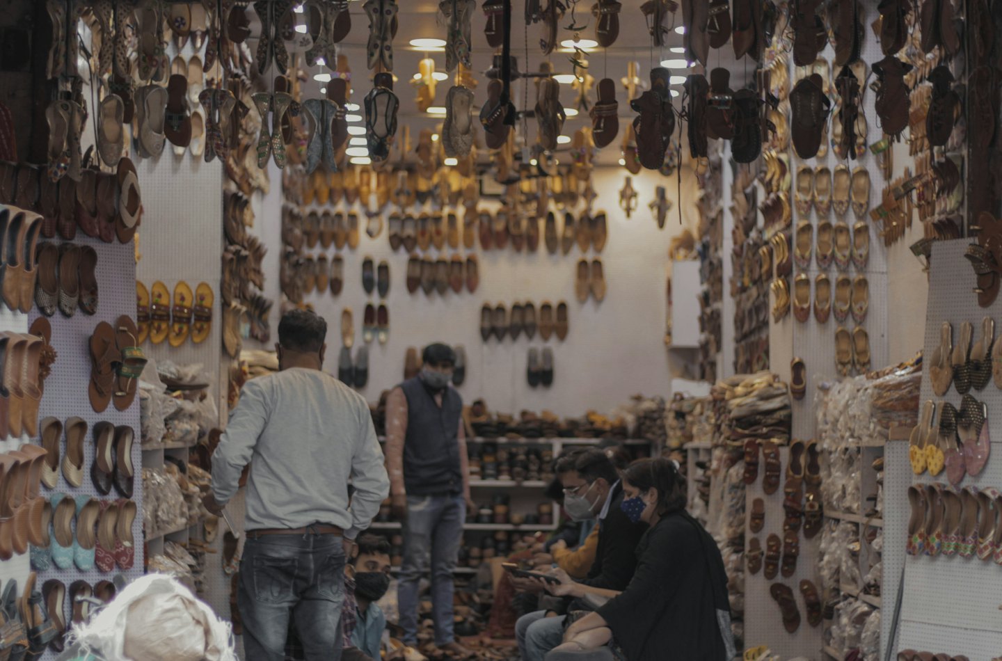 Customers browse leather sandals in a crowded traditional shoe store.