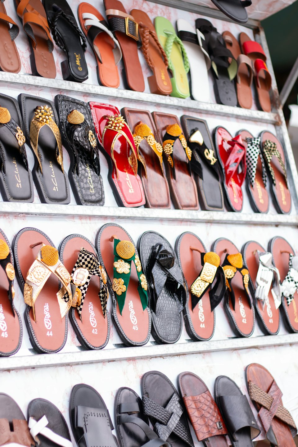 Colorful sandals and flip-flops arranged on white retail shelves.